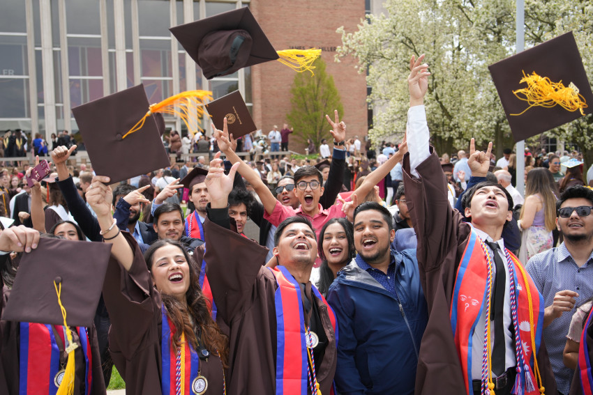Graduates toss their caps into the air.