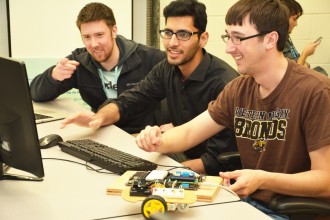 Three male students working with a computer.