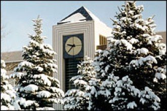 Photo of the outside of the WMU clock tower with snow on the roof and snow on trees in front.