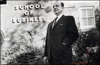 Arnold Schneider in front of the School of Business sign
