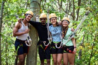 WMU WeSustain interns are shown during a retreat activity in ziplining gear in front of trees.