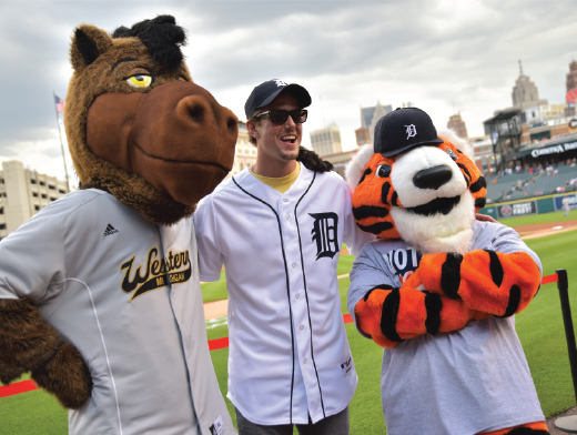 Pictured is a student posing with two mascots at a Tigers baseball game