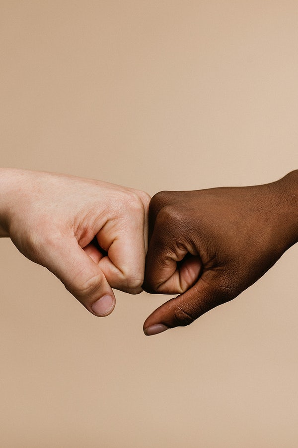 A white hand and a black hand fist bumping.