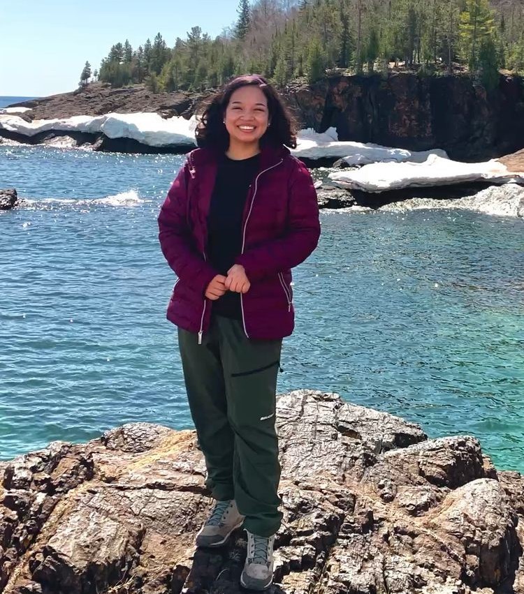 Jackie Chavarria standing on rocks near water in the Upper Peninsula.