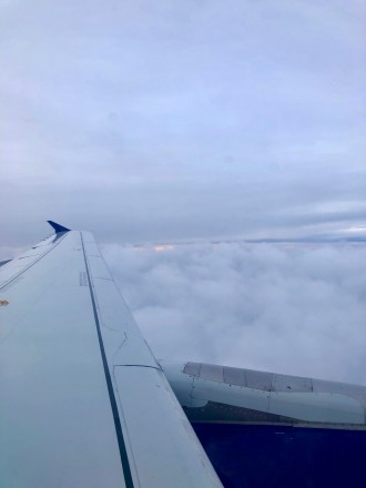 Looking out over the wing of a plane, clouds beneath