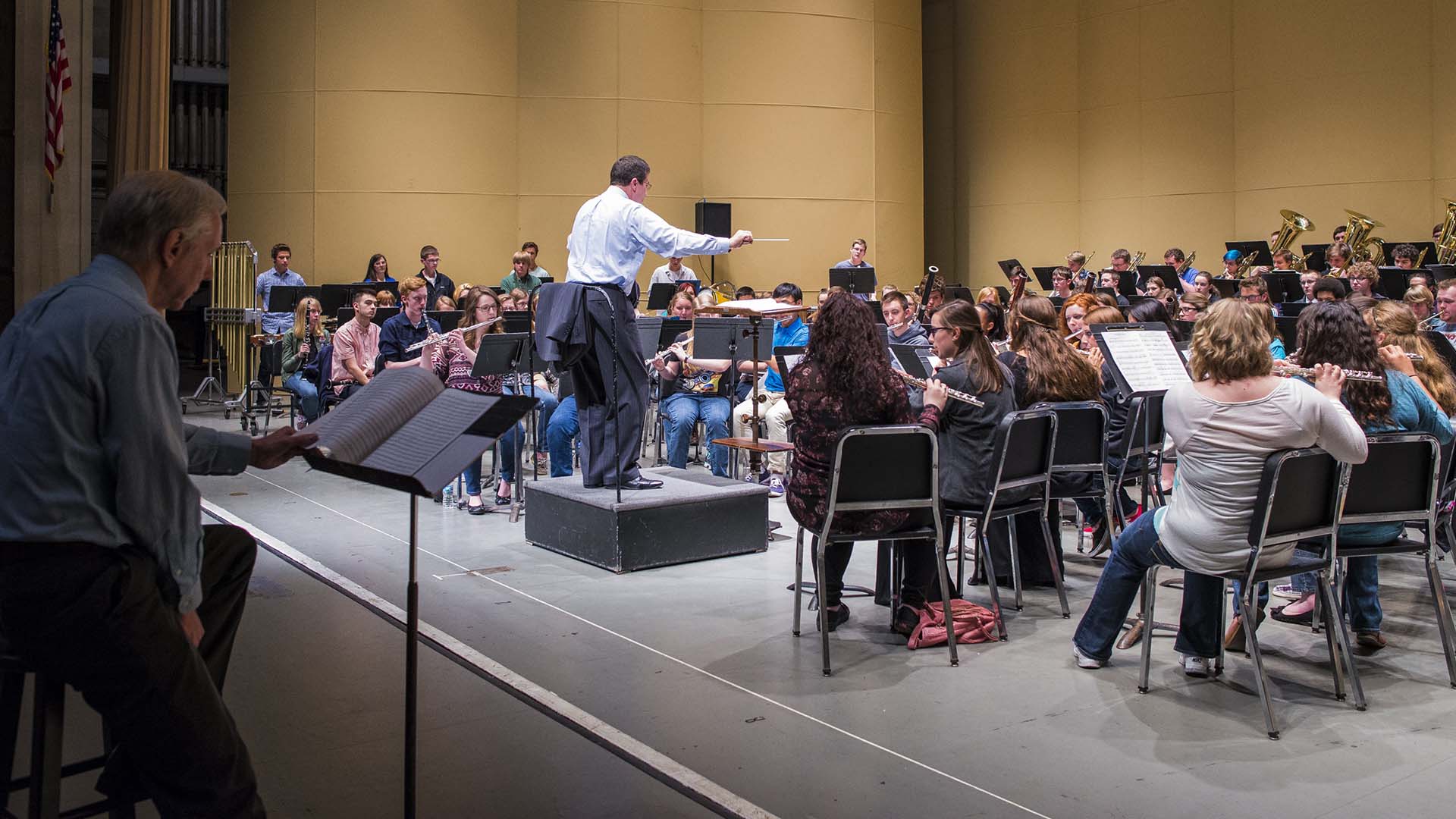 Spring Conference All-Star Band rehearsing with guest composer following the score seated on stage