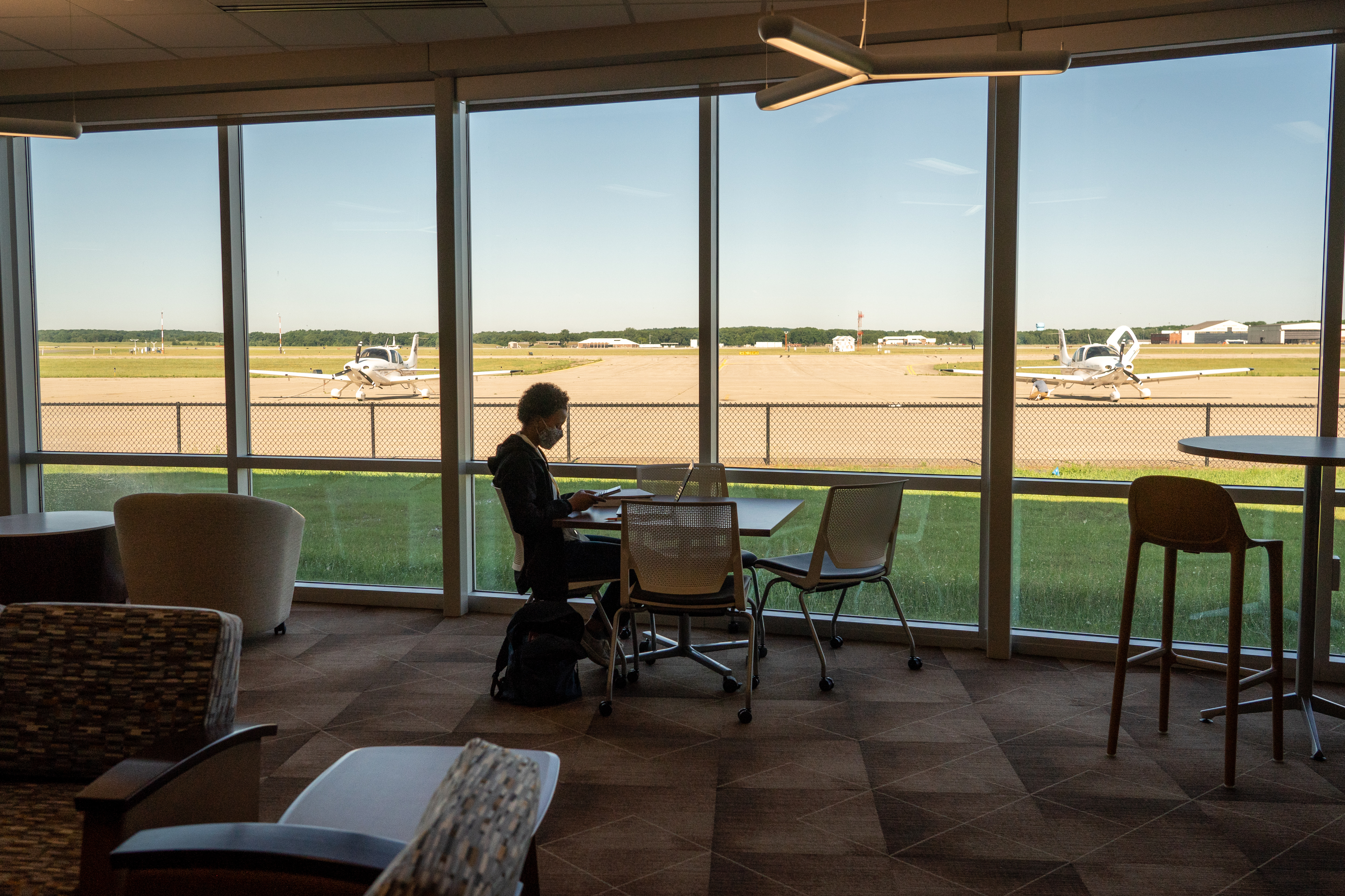 Adaora Osolu sits at a table next to windows that look out over the runway.