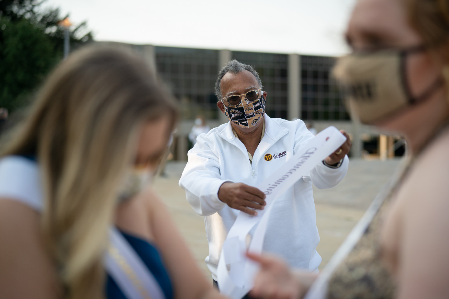 President Montgomery hands out a Homecoming sash.