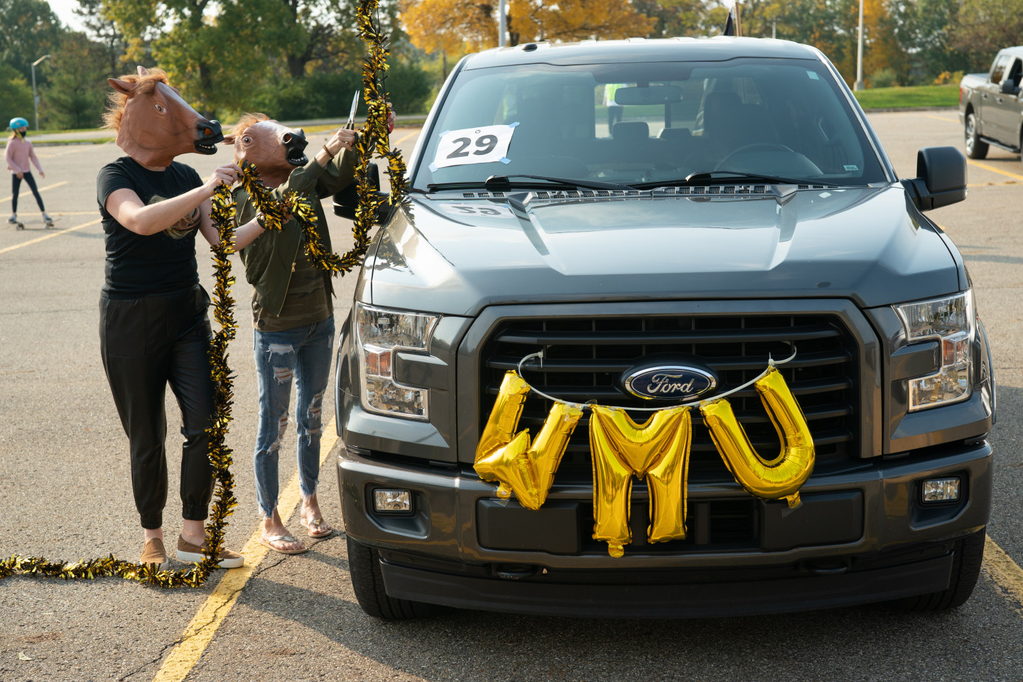 People in horse masks decorate a truck with WMU swag.