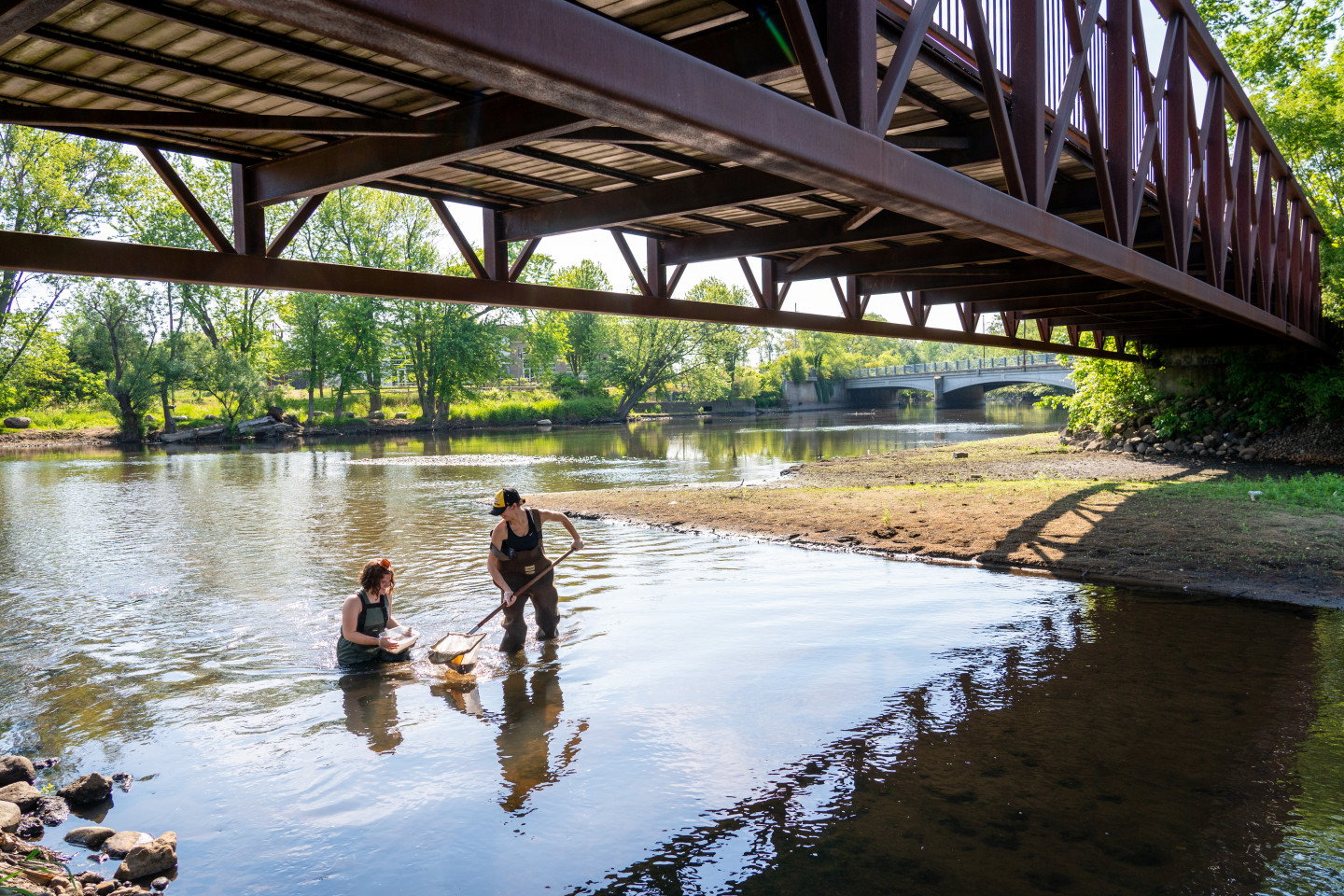 Students stand under a bridge in the Kalamazoo river.