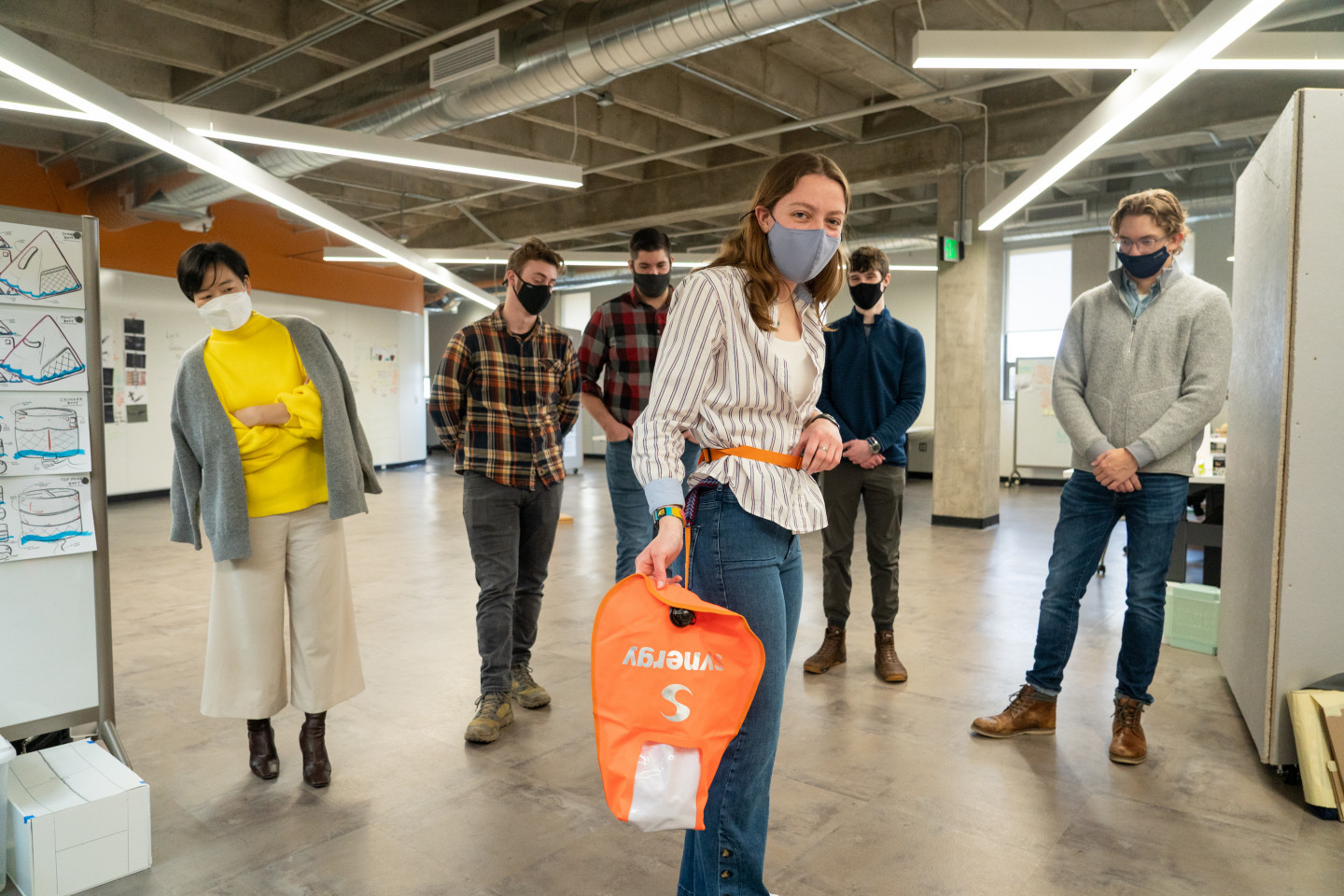 A student holds an orange bag that is tethered to her waist.