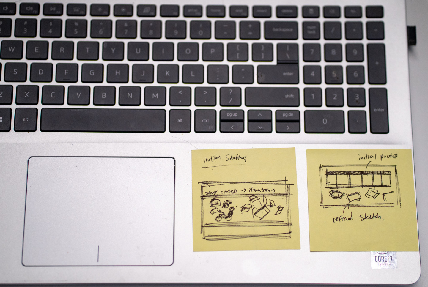 Post-It notes with design sketches on a laptop.