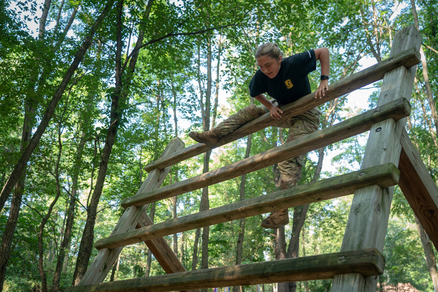 ROTC cadet Carly Ness climbs over an obstacle.