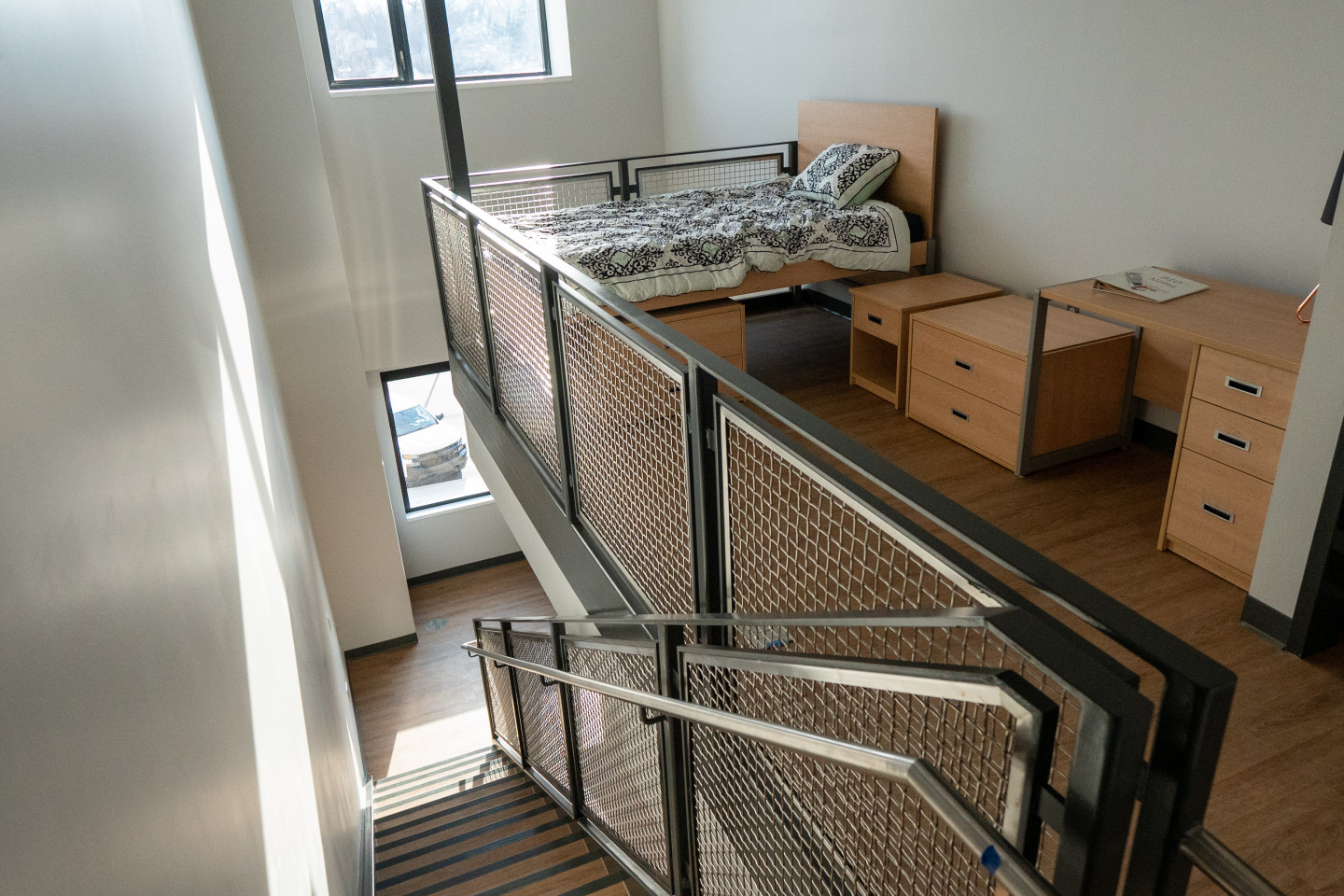 A bed in a loft area of an apartment.