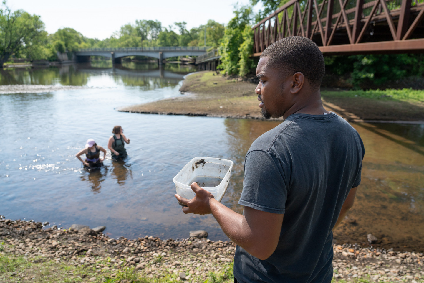 Jovaughn Carver holds a container of water next to a river.