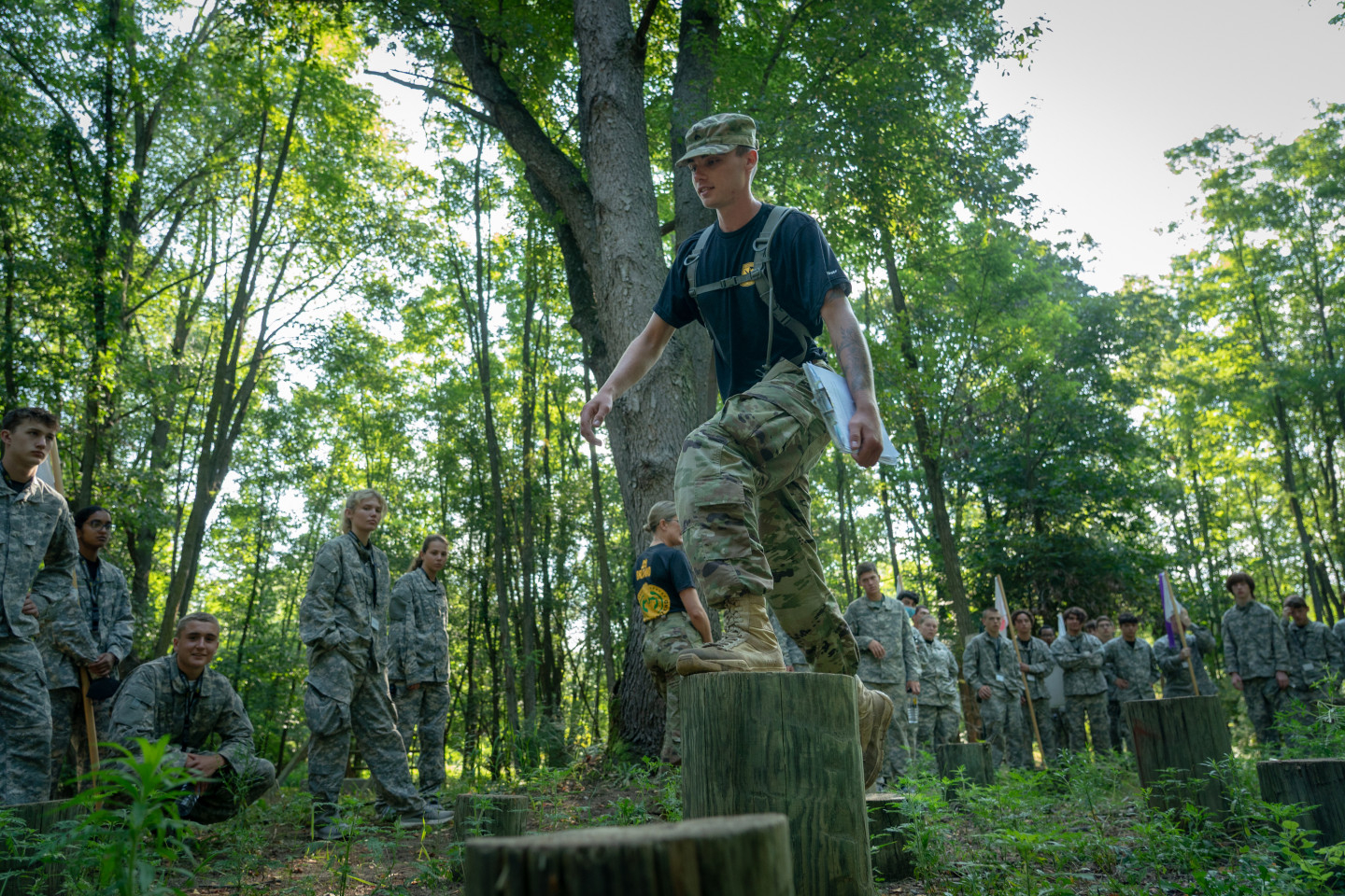 An ROTC cadet walks across stumps in an obstacle course.
