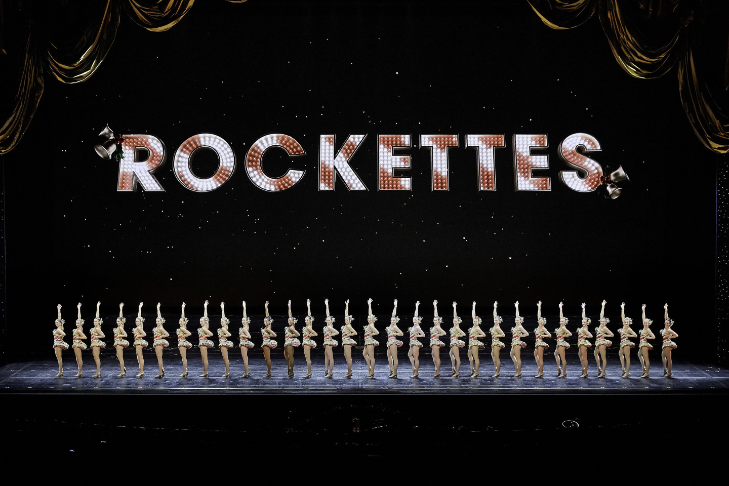 A line of dancers on a stage under a sign that reads "Rockettes."