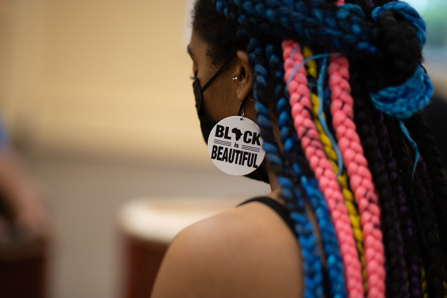 A girl wears an earring that reads "Black is Beautiful."