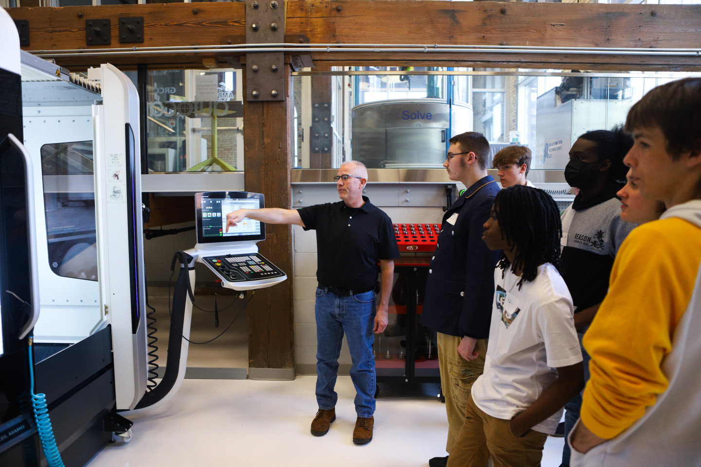 An instructor points a machine in the AMP lab.