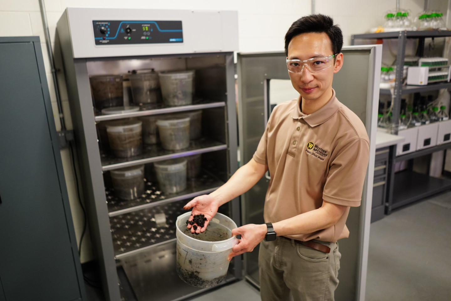 Jason Wang holds a bucket with soil in it.