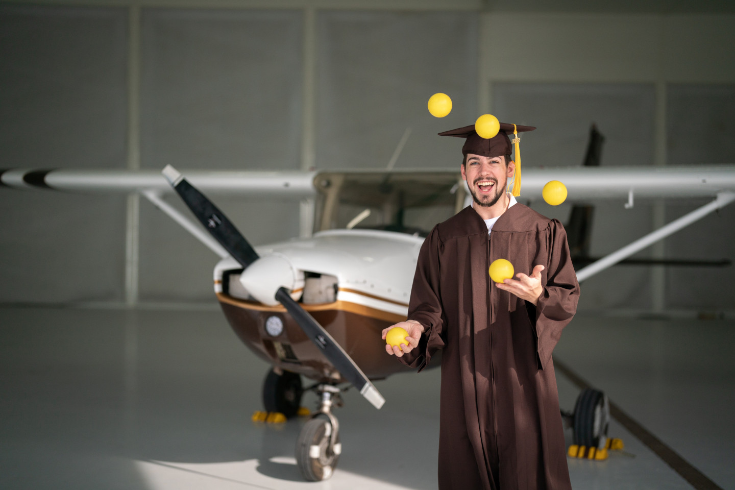 Kyle Albrecht juggles balls in front of an airplane.