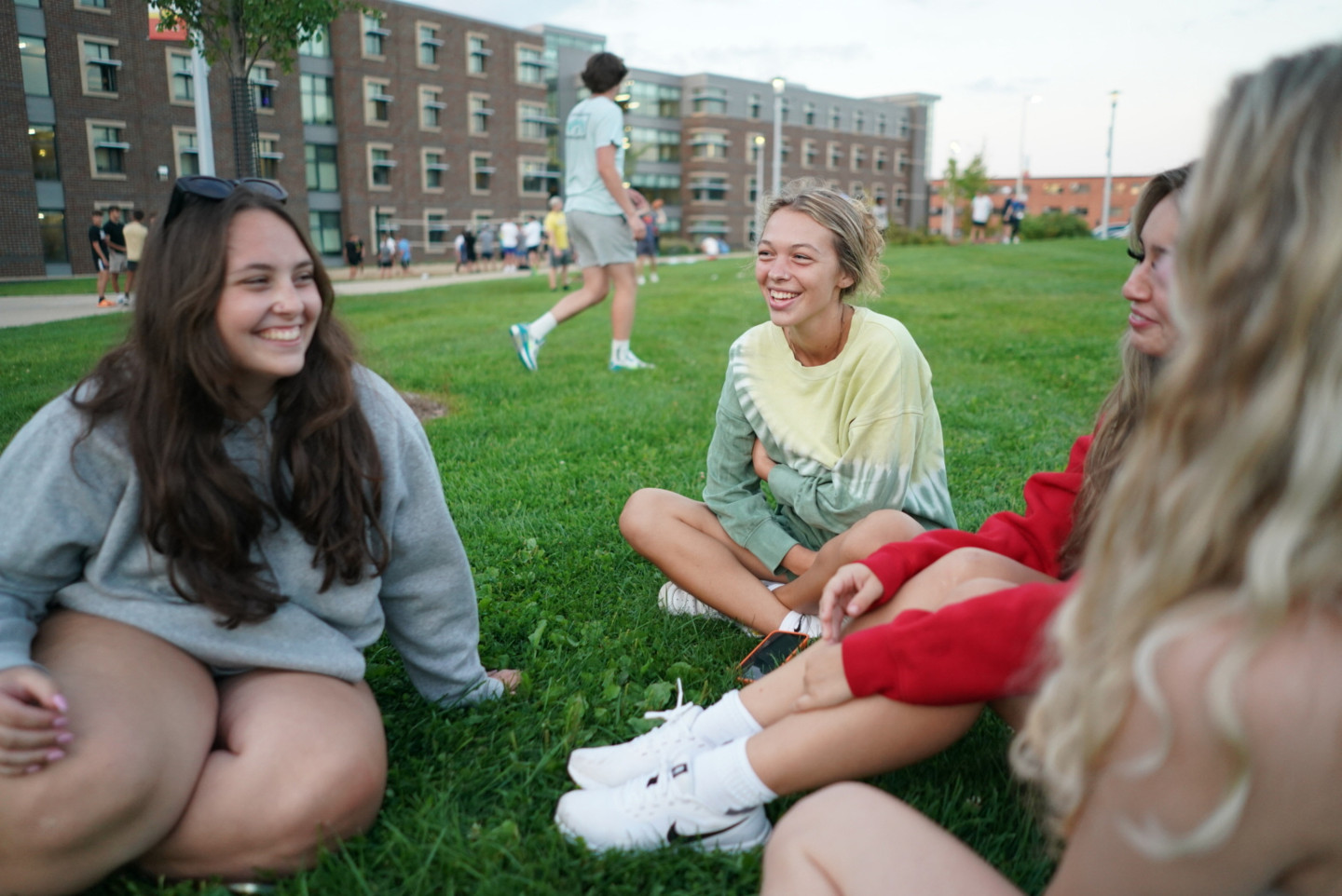 Students sit together on the grass.