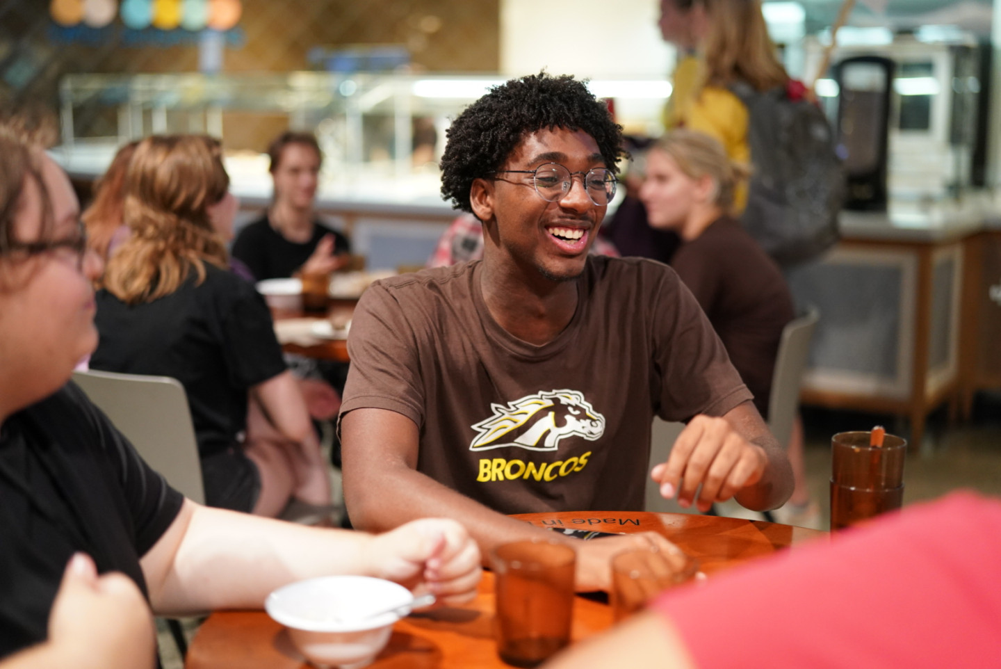 A student sits at a table in the dining hall.
