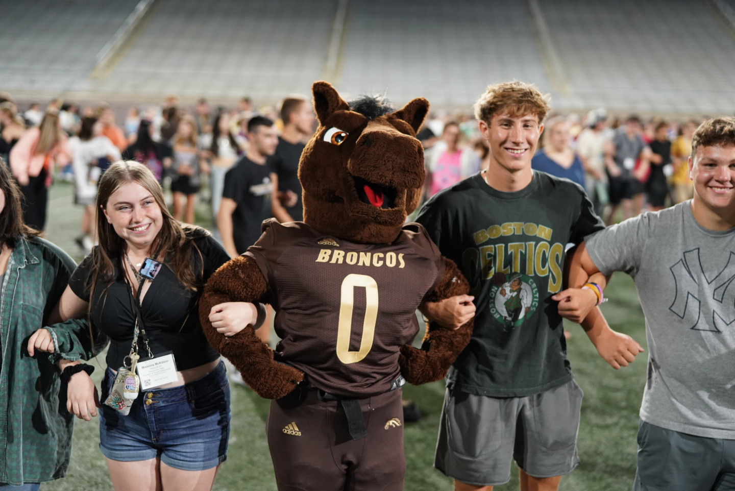 Buster Bronco links arms with students.