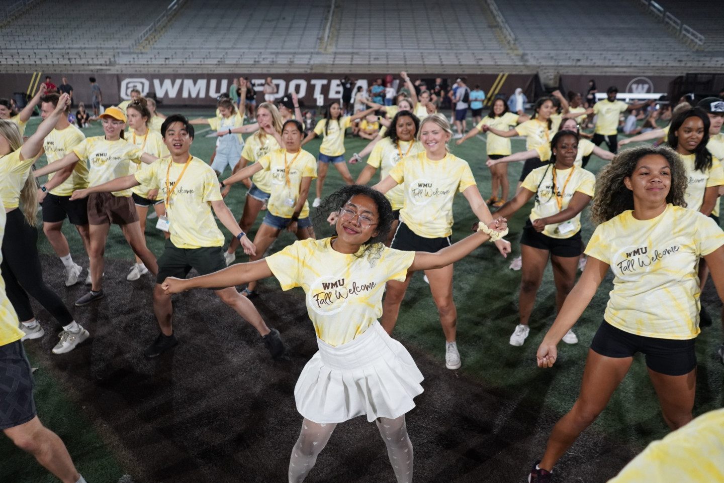 A group of students dances on the field.