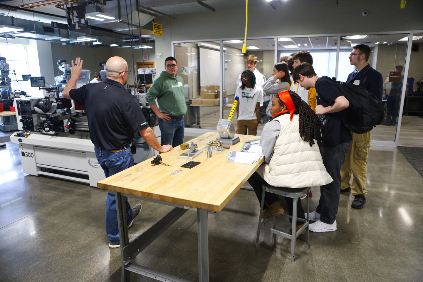 An instructor talks to students at a wooden table in the AMP Lab.