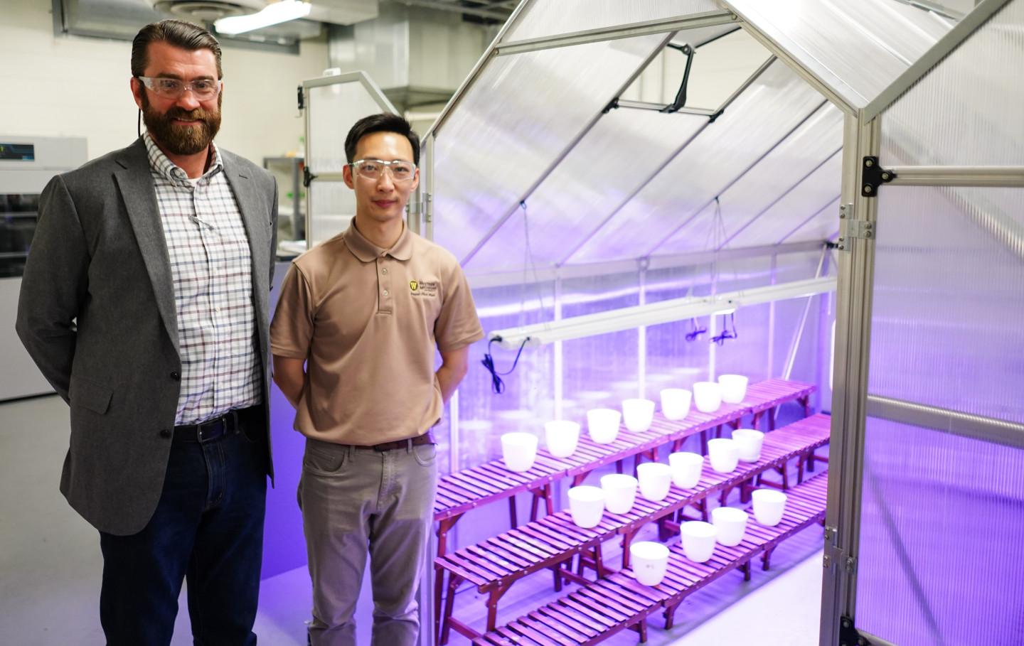 Lon Pschigoda and Jason Wang pose for a photo next to the lab's greenhouse.