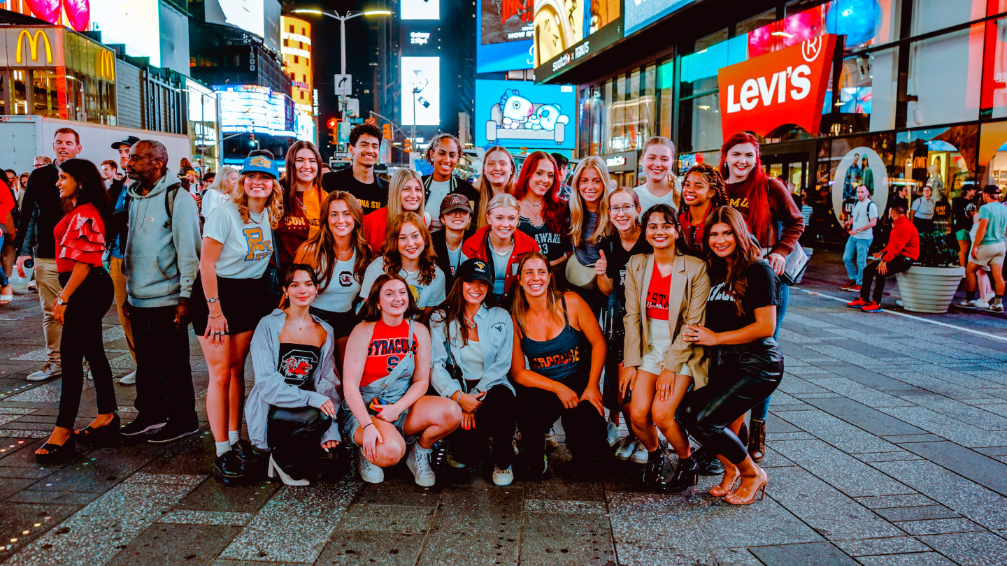 A photo of a large group of students posing in Times Square.
