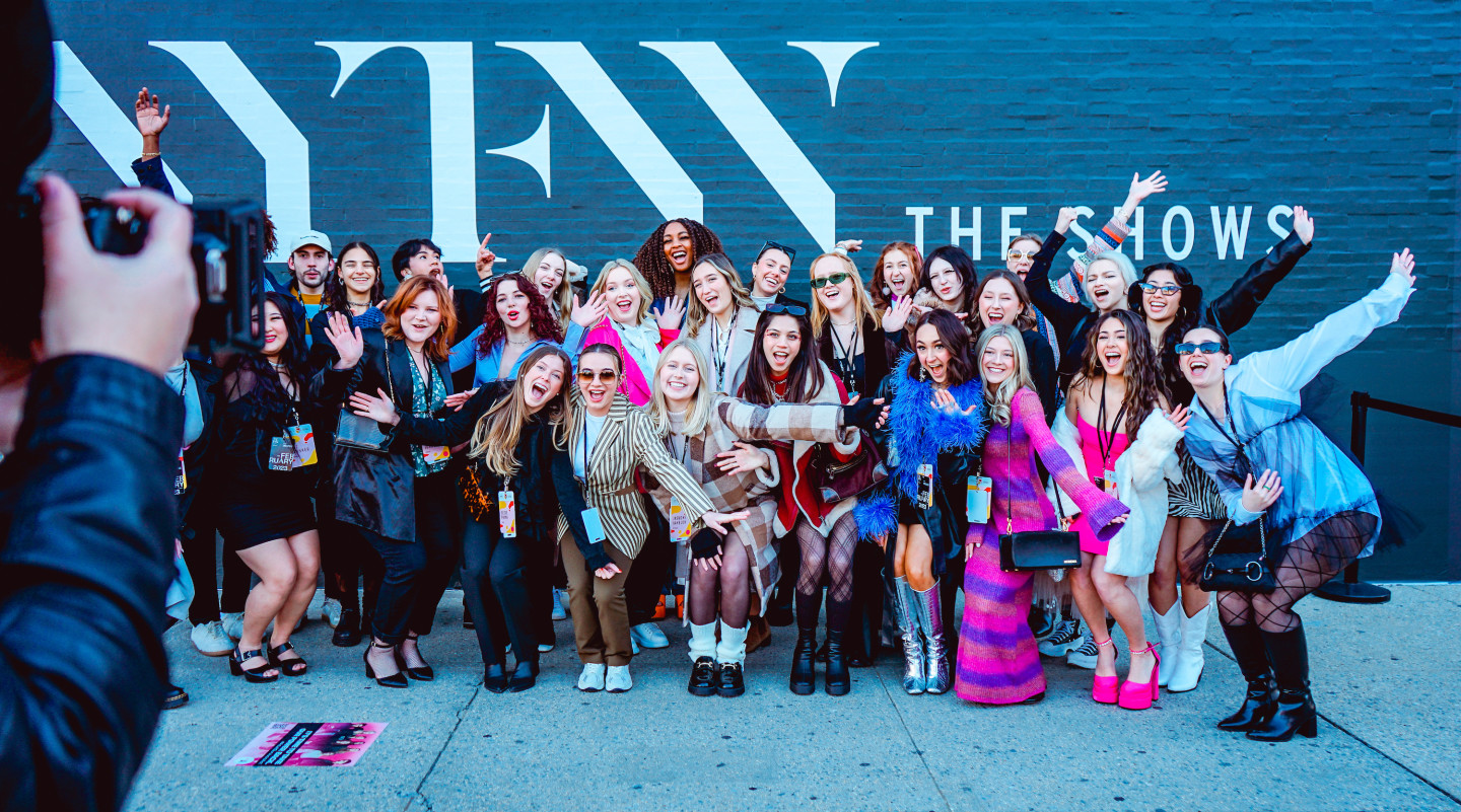 A group photo in front of a black wall with the letters "NYFW."