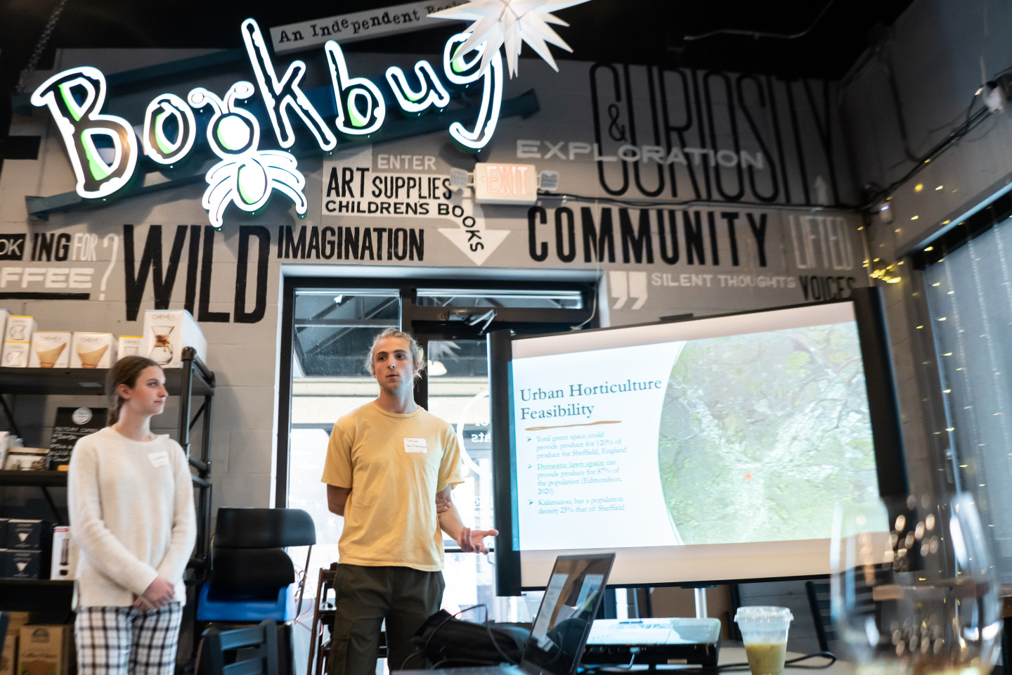 Joshua VanSlambrouck presents his team's concept in a coffee shop under a sign that reads "Bookbug."