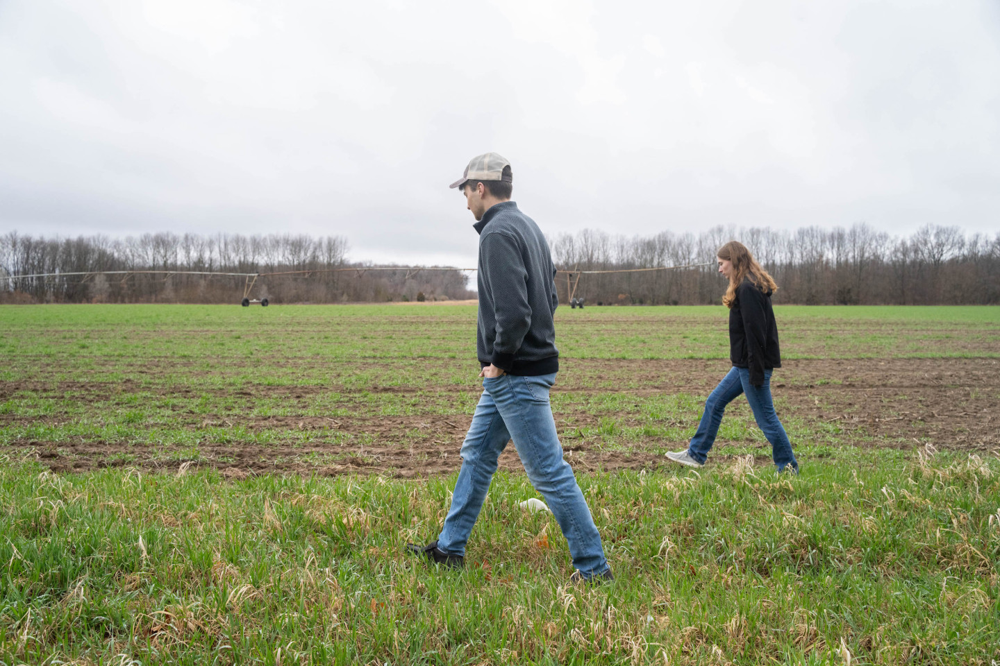 Two people walk through a field.