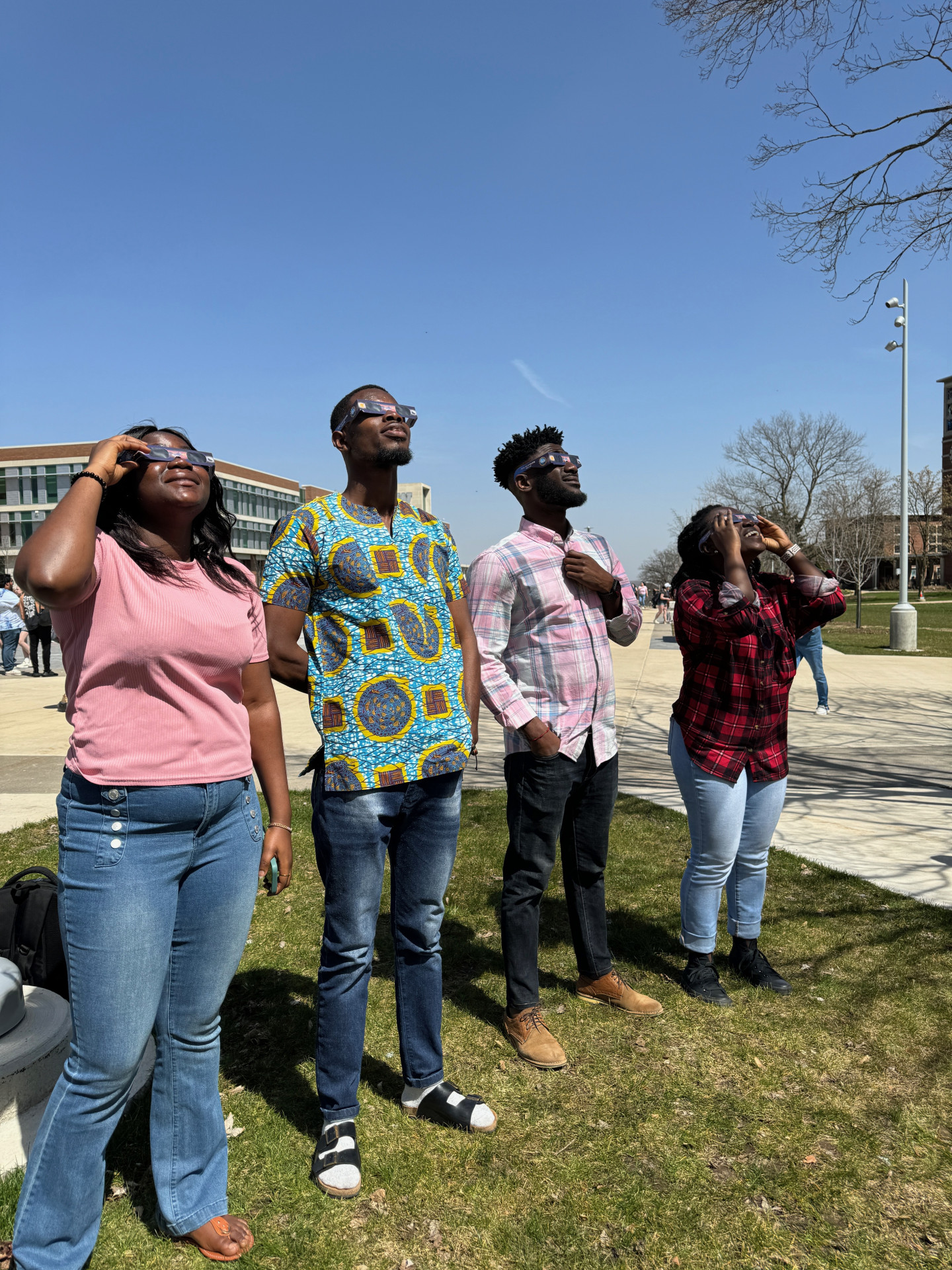 Students look toward the sky wearing eclipse glasses.