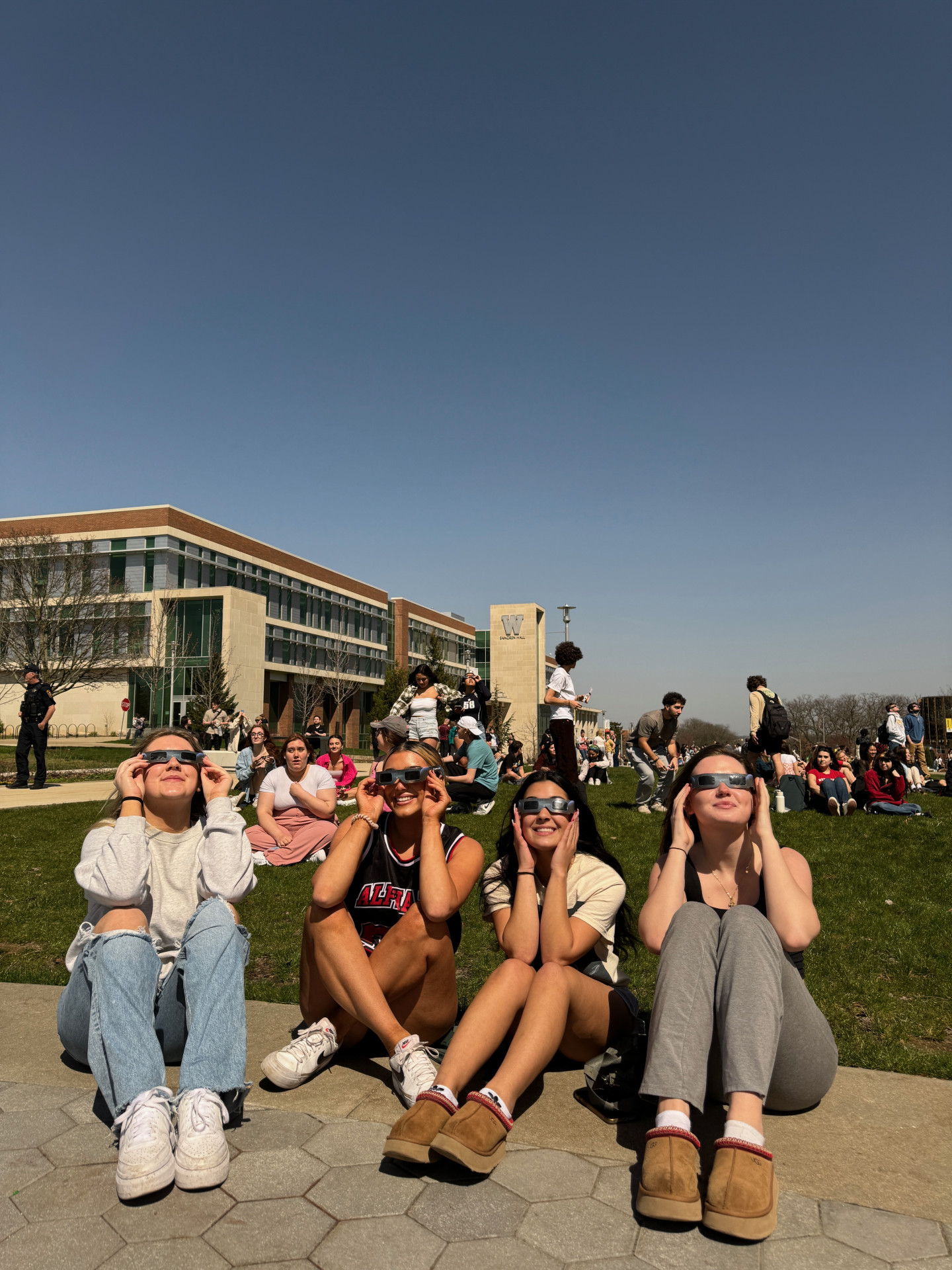 Students sit together wearing eclipse glasses.