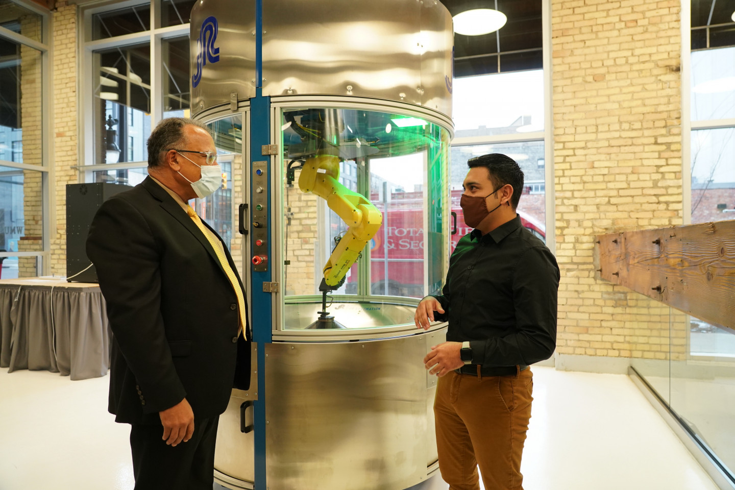 President Montgomery and Aunner Calderon stand in front of a piece of machinery at the WMU-Grand Rapids campus.