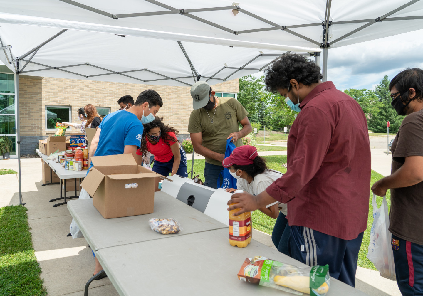 Volunteers wearing masks organize food under a tent at a collection event.
