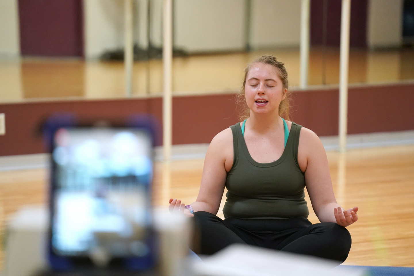 A student does yoga while livestreaming the class on Facebook.