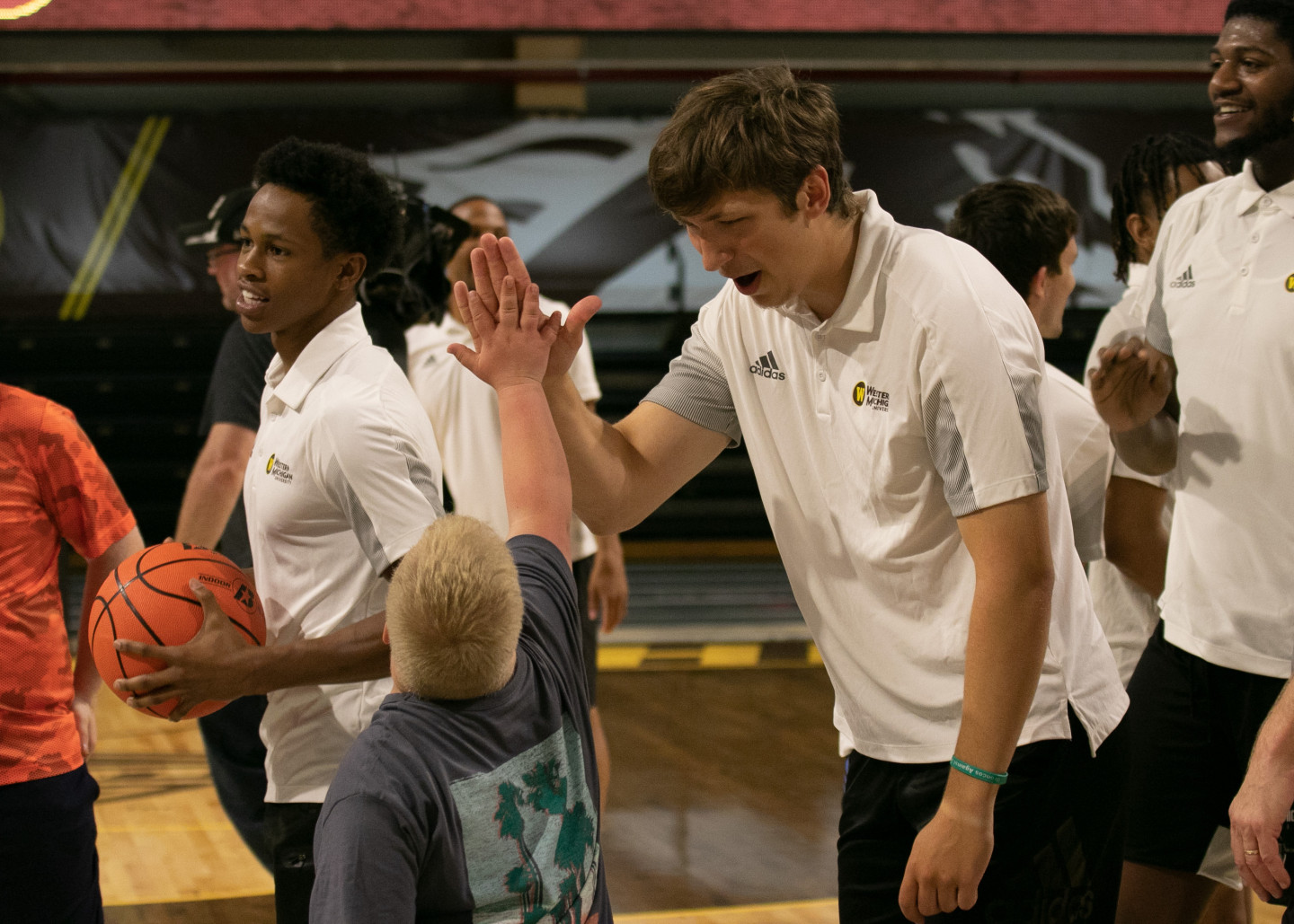A men's basketball player high fives a participant.