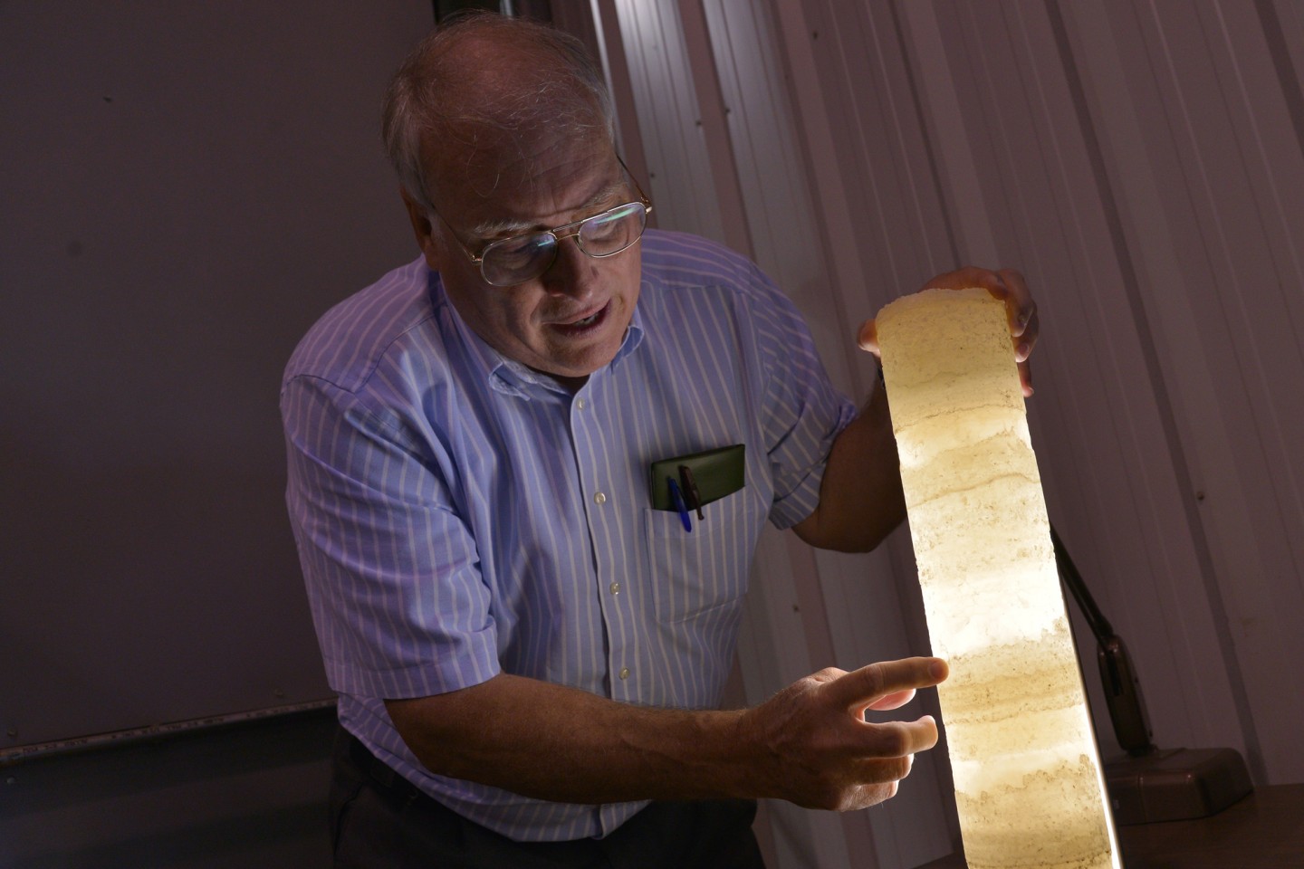 Dr. William Harrison holding a translucent rock core layered with potash.