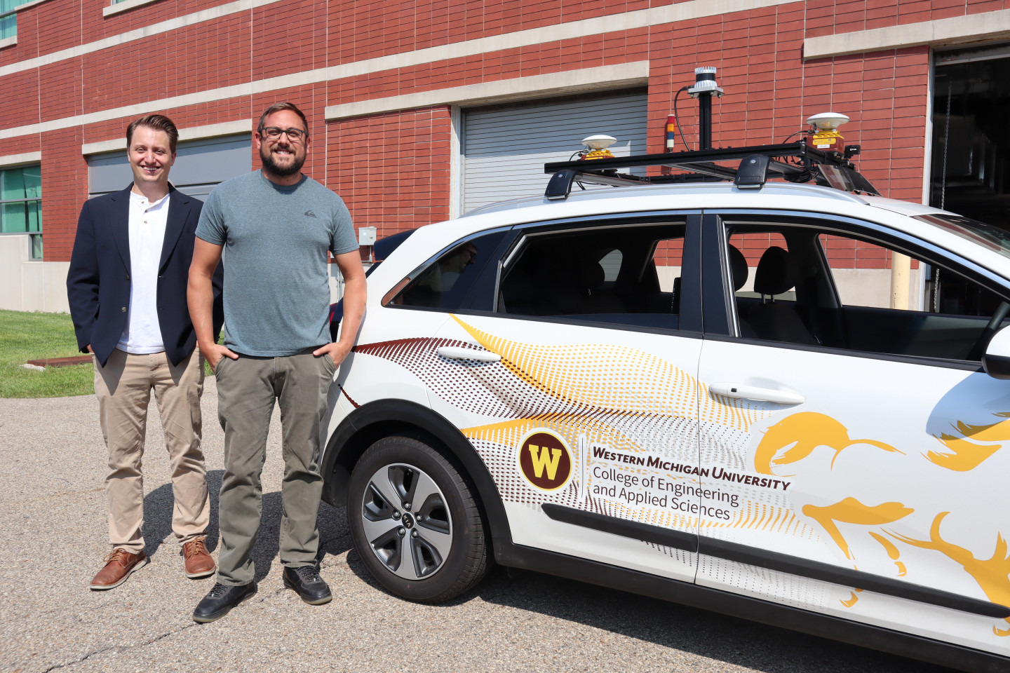 Dr. Zachary D. Asher, left, and Nicolas Brown, a doctoral student in the Efficient and Autonomous Vehicles Lab, stand next to their autonomous research vehicle.