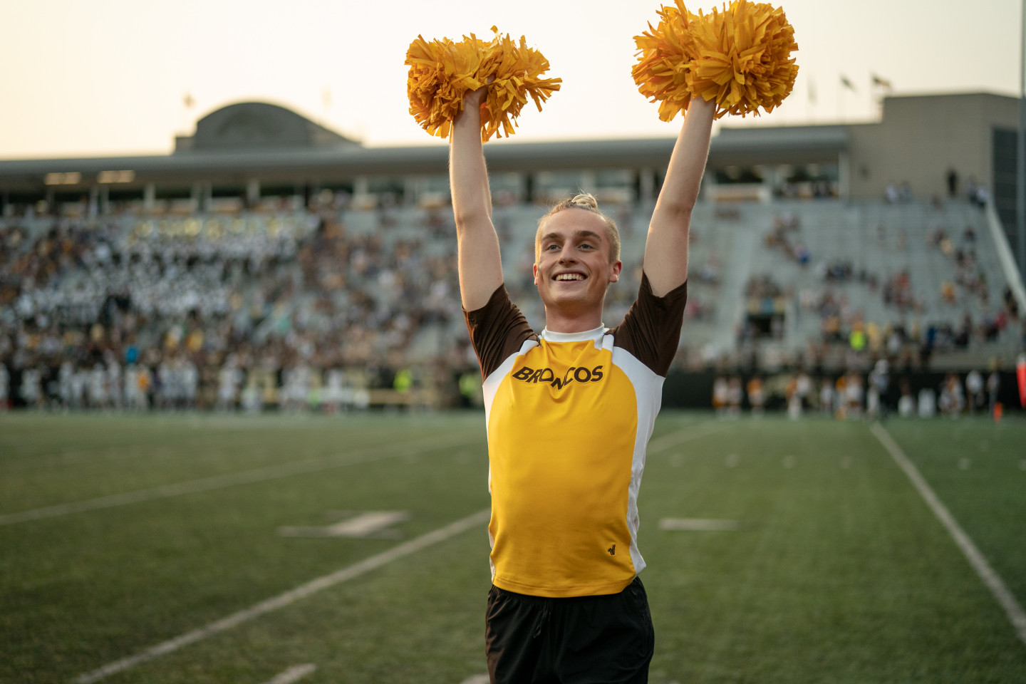 Nik McNees performs with pompoms held high in the air.
