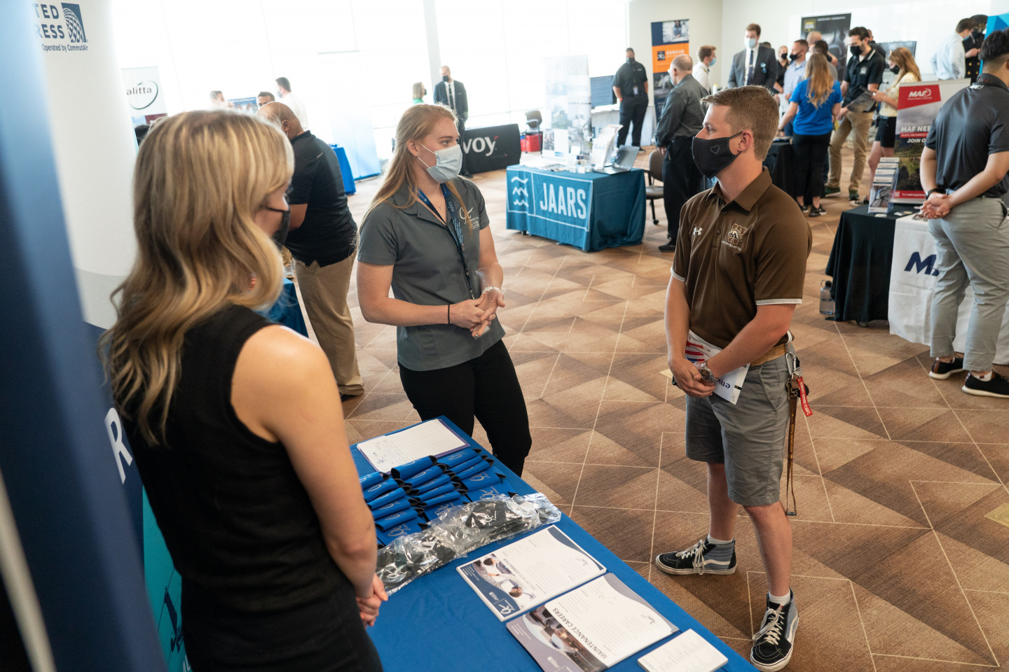 A student listening to two recruiters at a job fair at the Aviation Education Center.