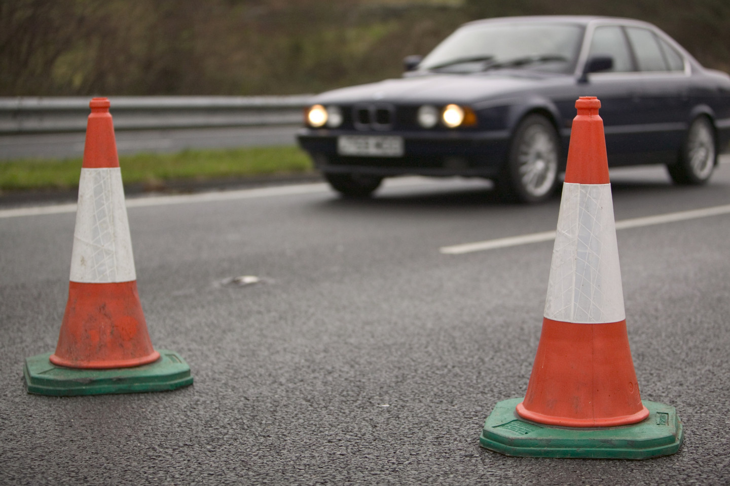 Traffic cones with a car on the road.