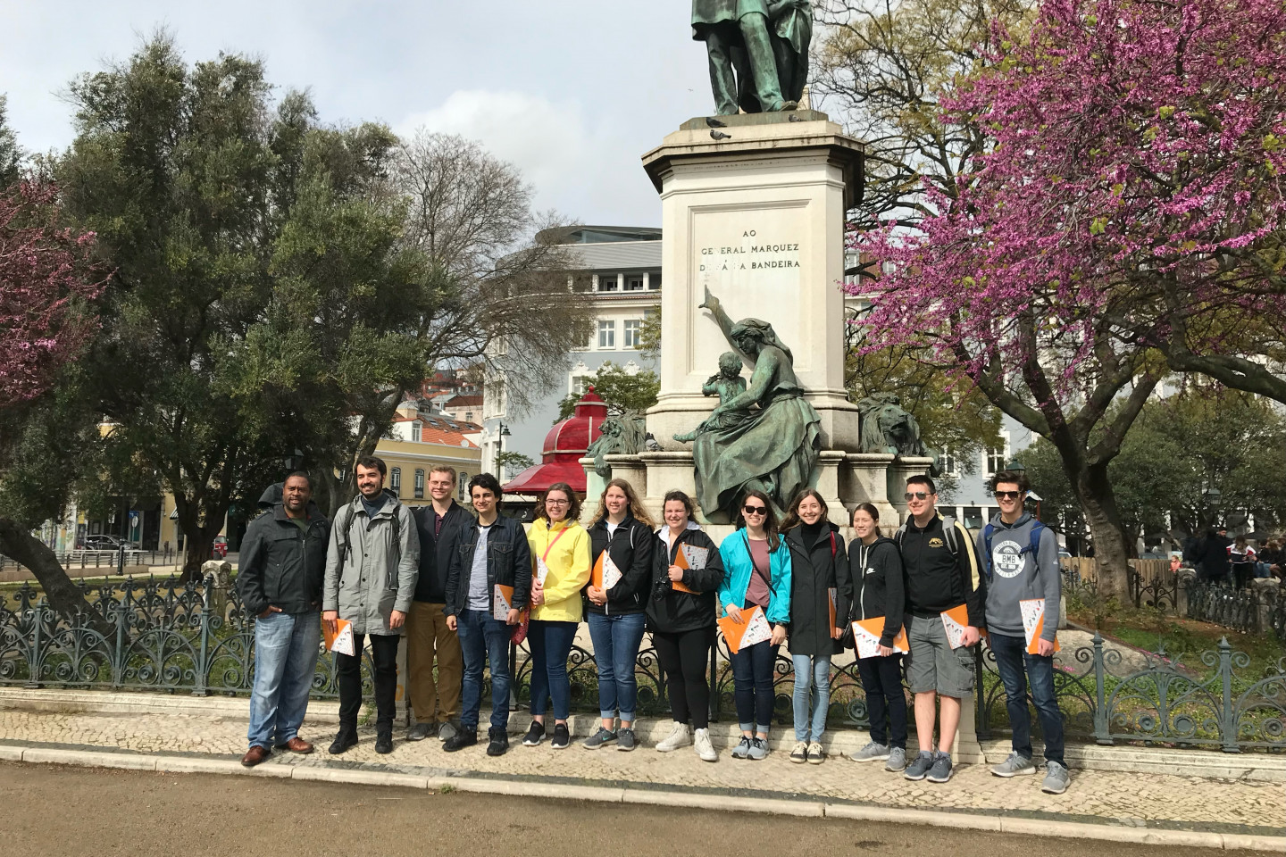 A group of students stands in front of a statue in Portugal.