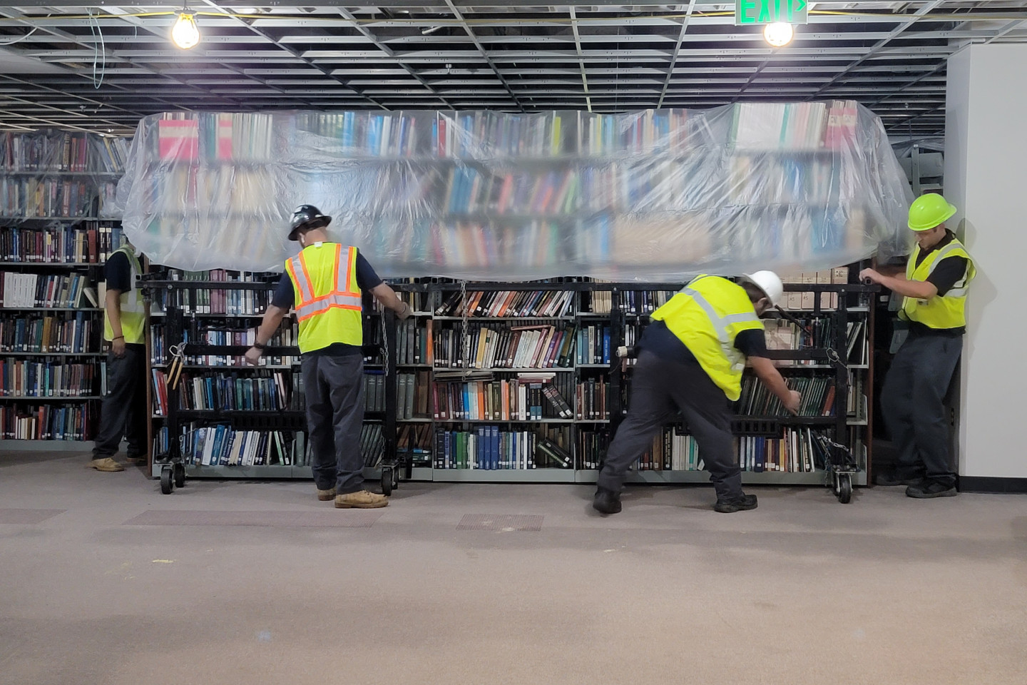 Workers moving bookshelves to make room for construction on Waldo Library's lower level