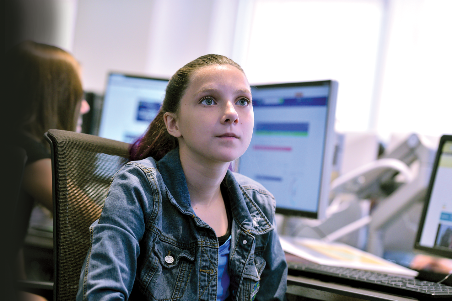A girl looks at a computer screen in a computer lab.
