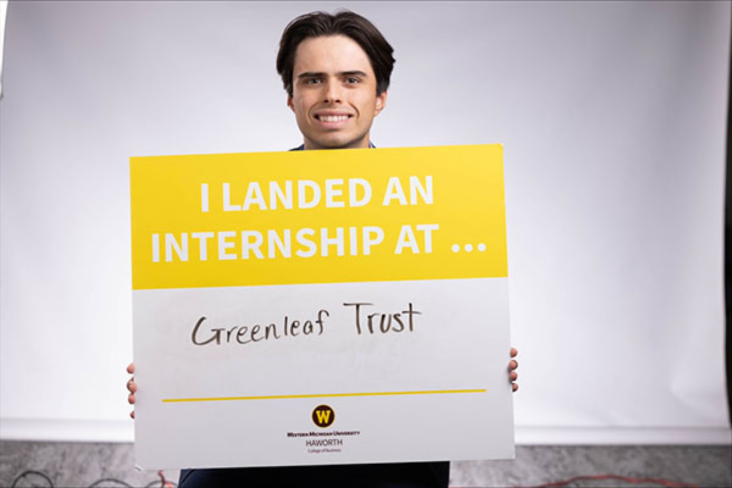 Enrique Domeier holds a sign showing his internship at Greenleaf  Trust